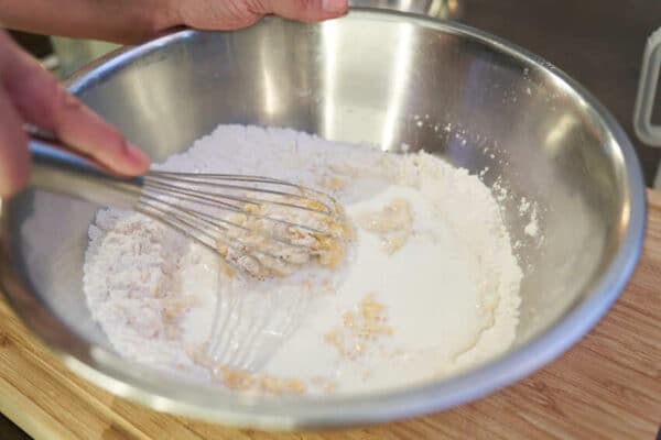 Milch und Mineralwasser unter ständigem Rühren, langsam hineingießen.